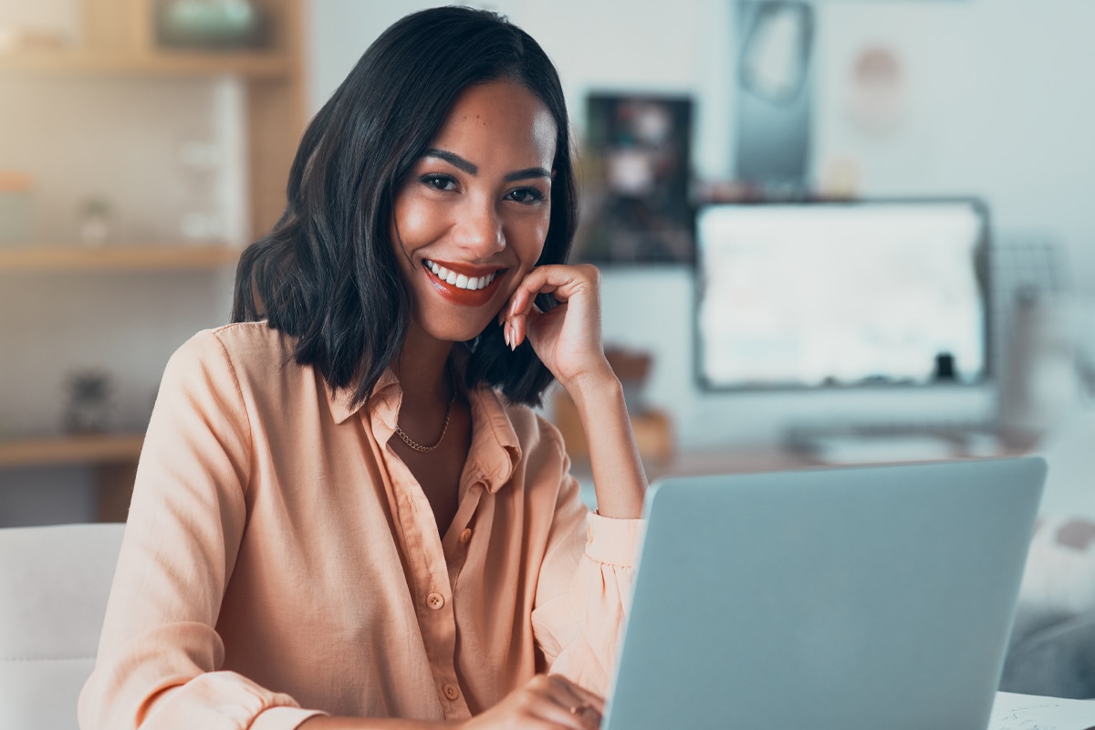 Business owner smiling while working on SEO strategy on a laptop.