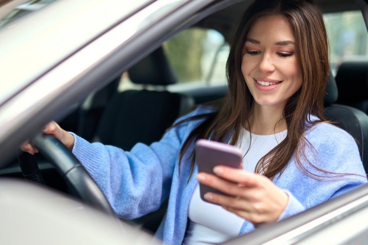 Woman using a smartphone for a near me search while sitting in her car.